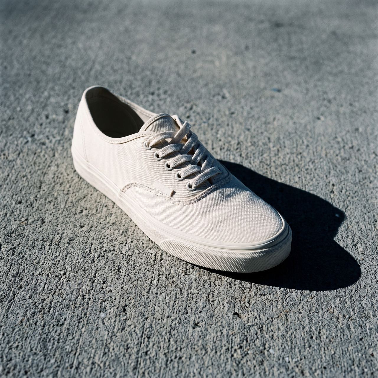 Une paire de baskets en toile écrue posée sur du béton : le diamant est incrusté dans l’image, en haut à gauche.